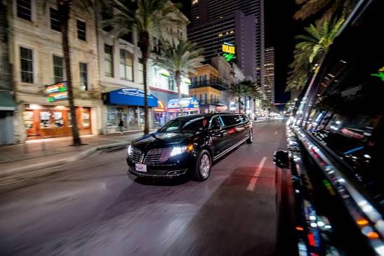 Black stretch limousine driving through the city at night